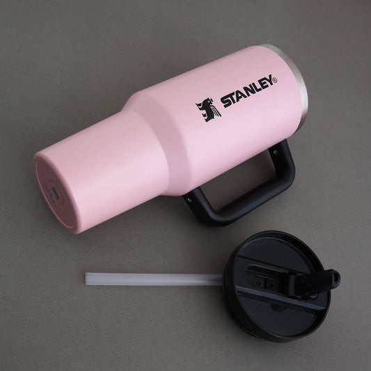 Pink Stanley tumbler with black lid and straw on a gray background