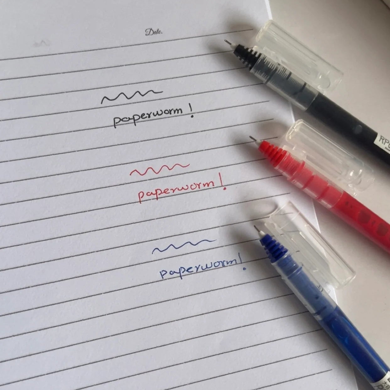Notebook with handwritten text and two pens on a light background