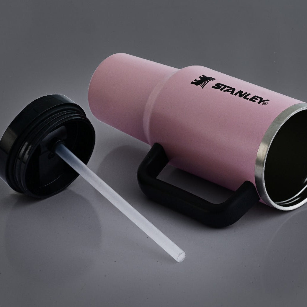 Pink Stanley tumbler with black lid and straw on a gray background