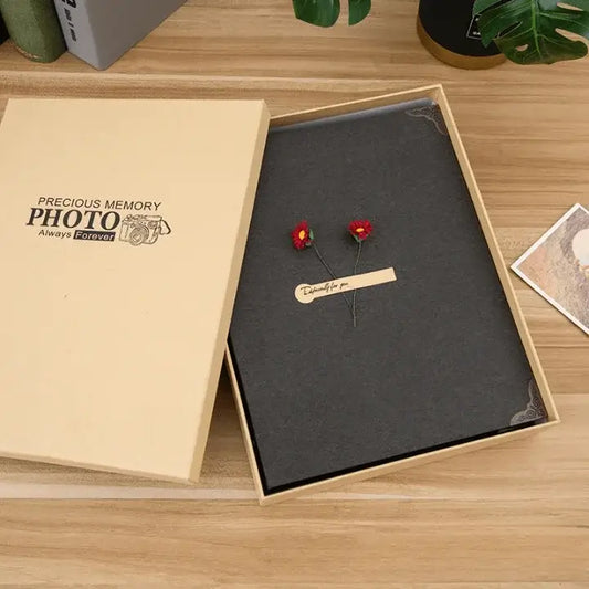 Decorative photo frame with red flowers and a wooden tag on a wooden surface.