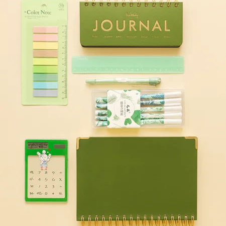 Collection of green stationery items including a journal, pens, and a color swatch on a beige background.