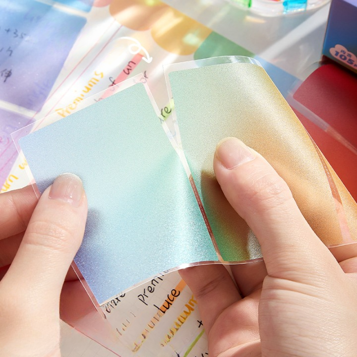 Colorful gradient sticky notes held by a person with a blurred background of more sticky notes.