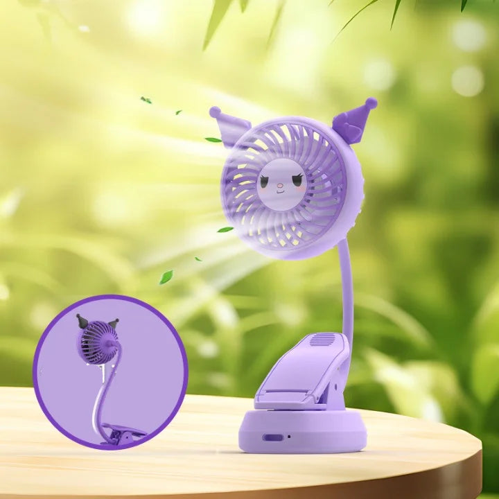 Purple cartoon-style fan with a clip on a wooden surface with a green blurred background