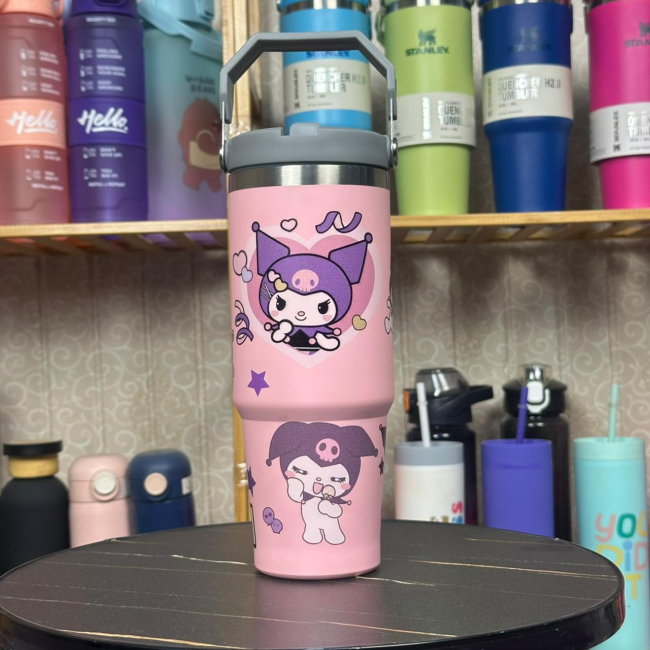 Pink tumbler with cartoon character design on a shelf with other colorful tumblers.