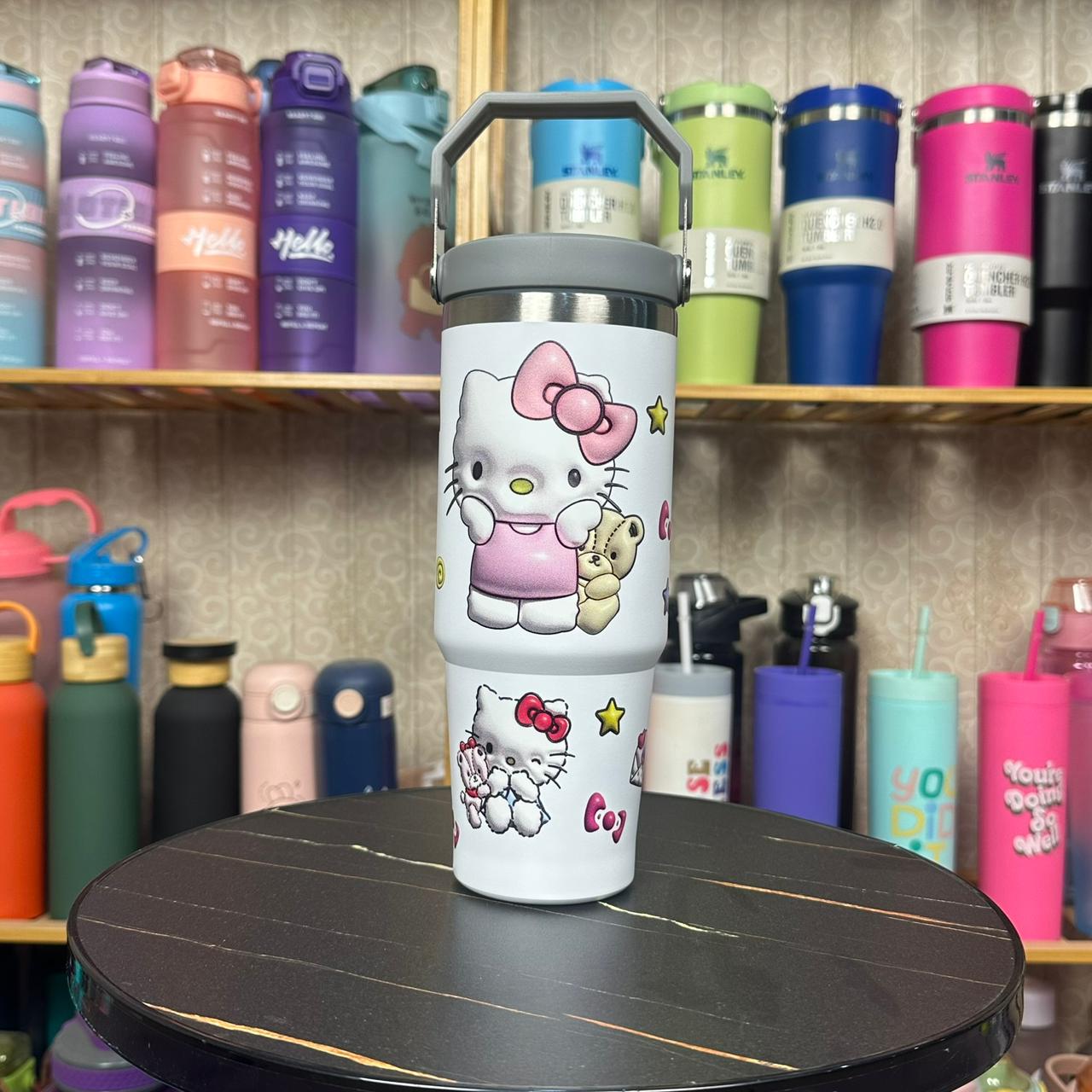 Hello Kitty-themed tumbler on a black surface with a colorful background of similar tumblers.
