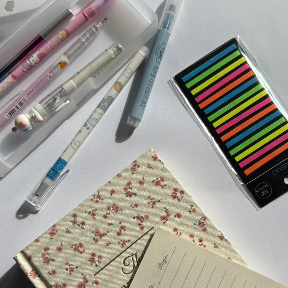 Notebook, pens, and highlighter on a white surface