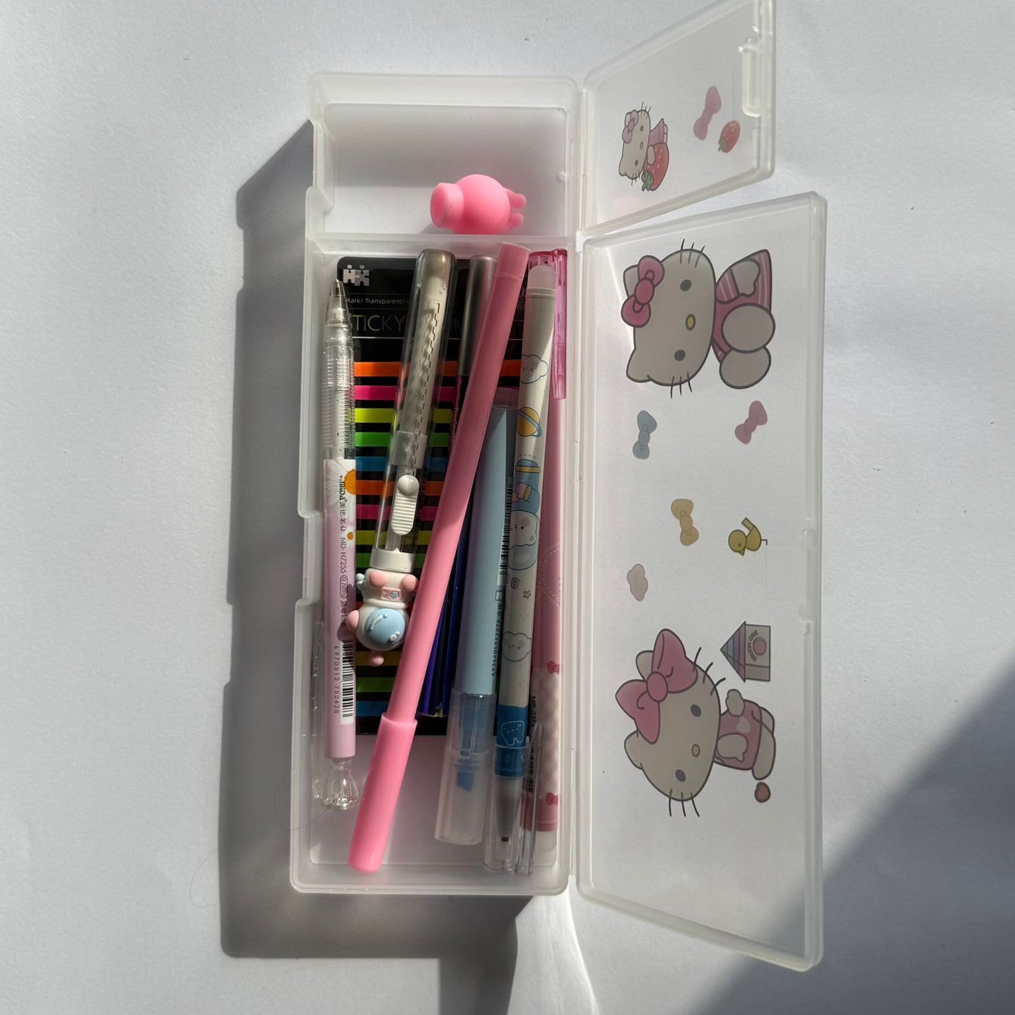 Pen case with stationery items and Hello Kitty designs on a white background