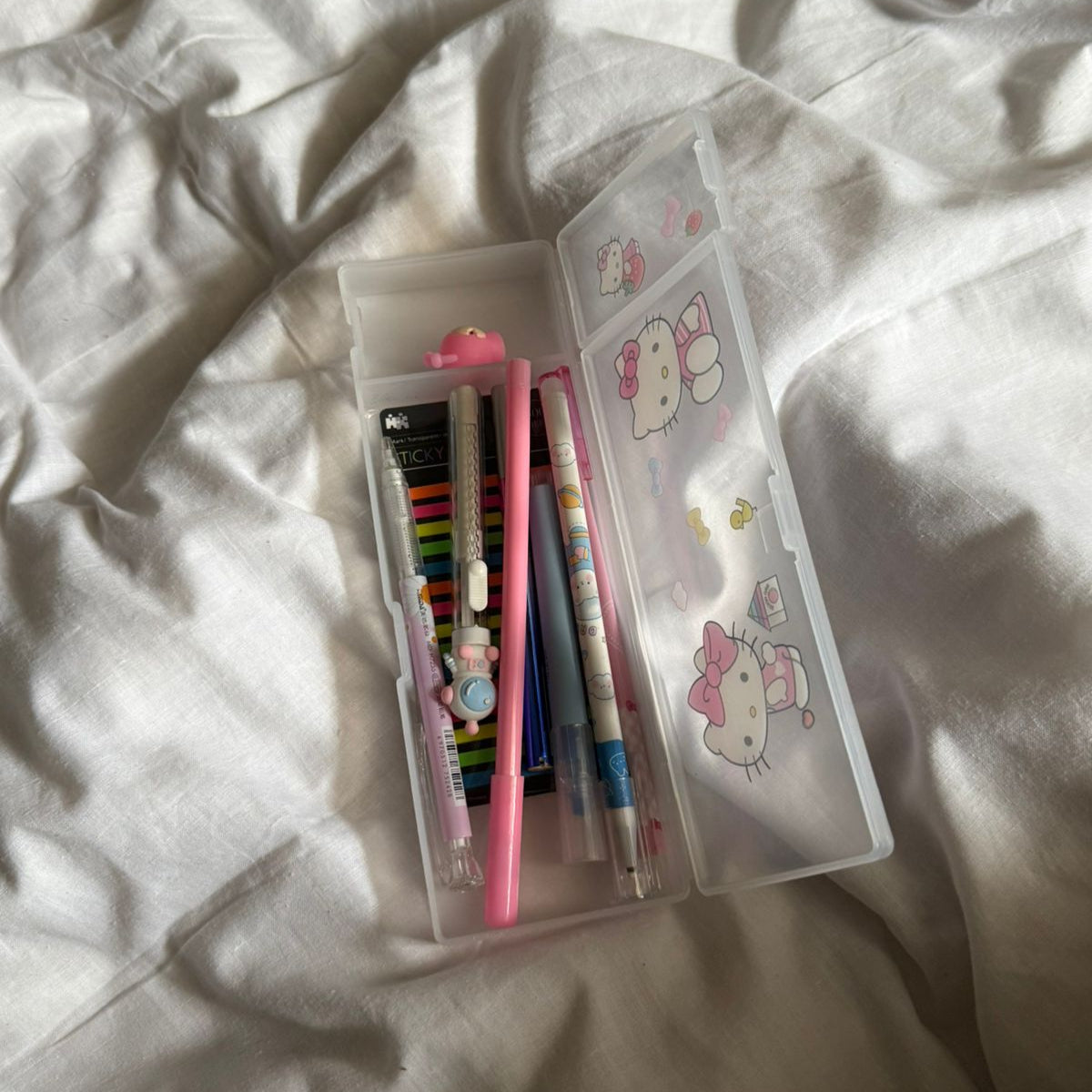 Pencil case with stationery items on a white fabric background