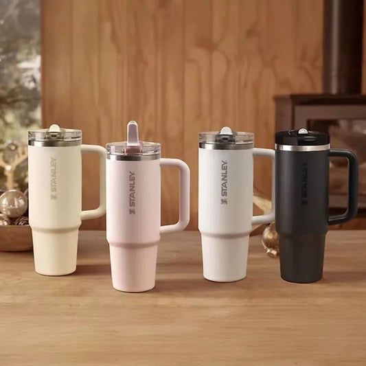 Four Stanley mugs on a wooden surface with a blurred background