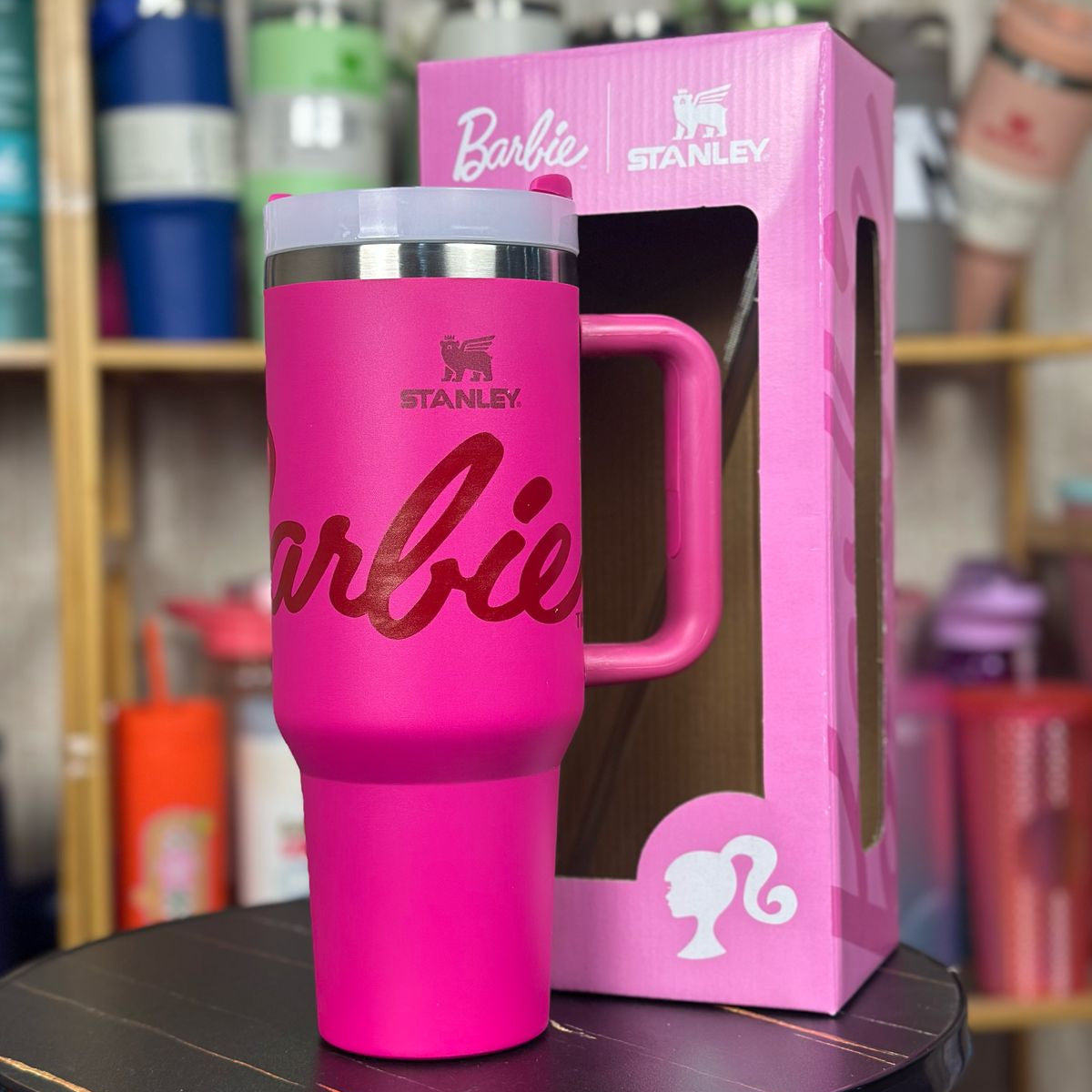 Pink Stanley mug with Barbie logo in front of its packaging on a table.