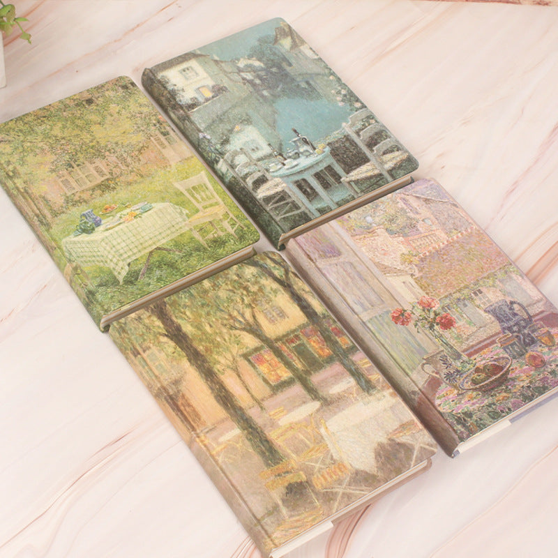 Three notebooks with scenic covers on a light wooden surface