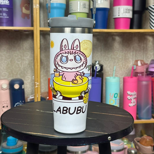 White tumbler with cartoon character on a black stool against a background of colorful tumblers.