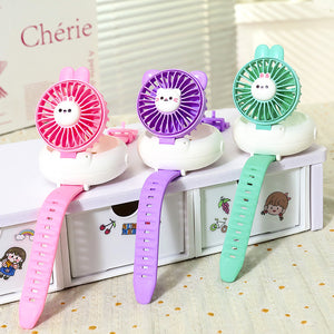 Three colorful handheld fans with cartoon faces on a white surface.