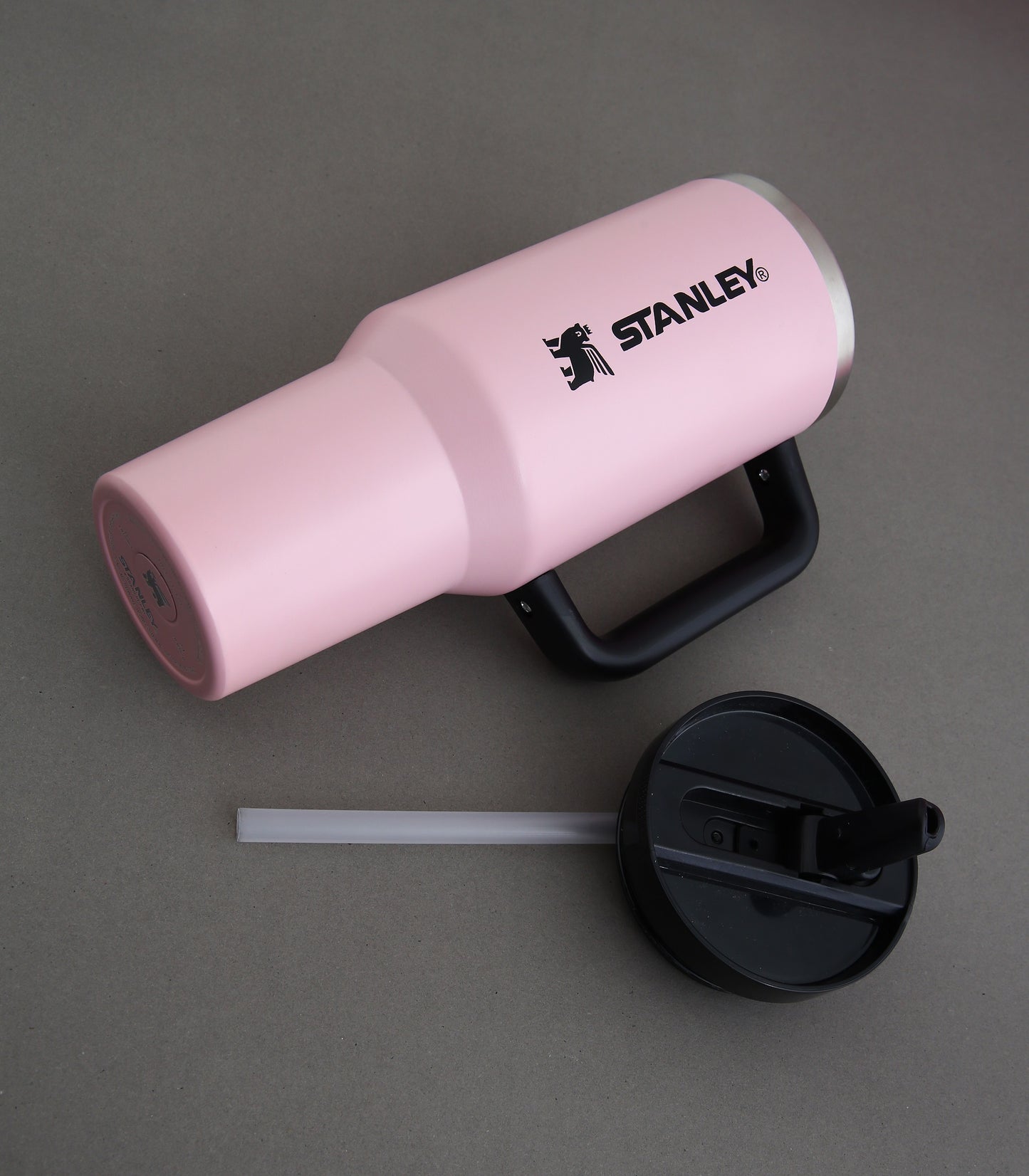 Pink Stanley tumbler with black lid and straw on a gray background