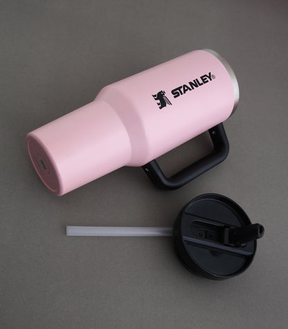 Pink Stanley tumbler with black lid and straw on a gray background