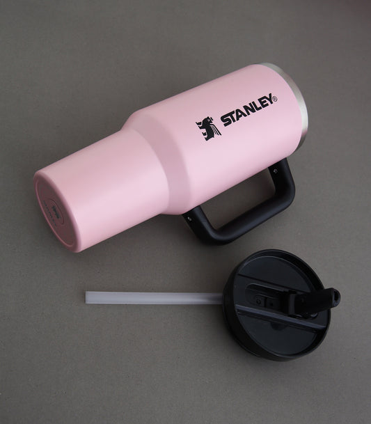 Pink Stanley tumbler with black lid and straw on a gray background