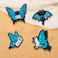 A set of four enamel pins designed as cats with butterfly wings, in blue, black, white, and yellow colors.