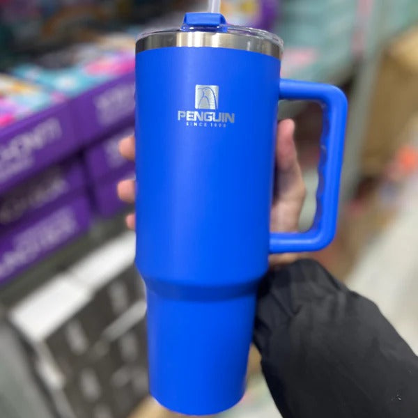 Blue insulated mug with handle held by a person in a store setting