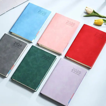 Set of colorful 2026 planners on a light surface with a laptop and tulips.
