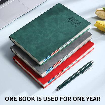 Stack of green, gray, and red notebooks with a pen on a white surface.