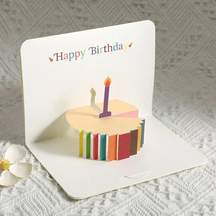 Colorful birthday cake card with a candle on a textured surface