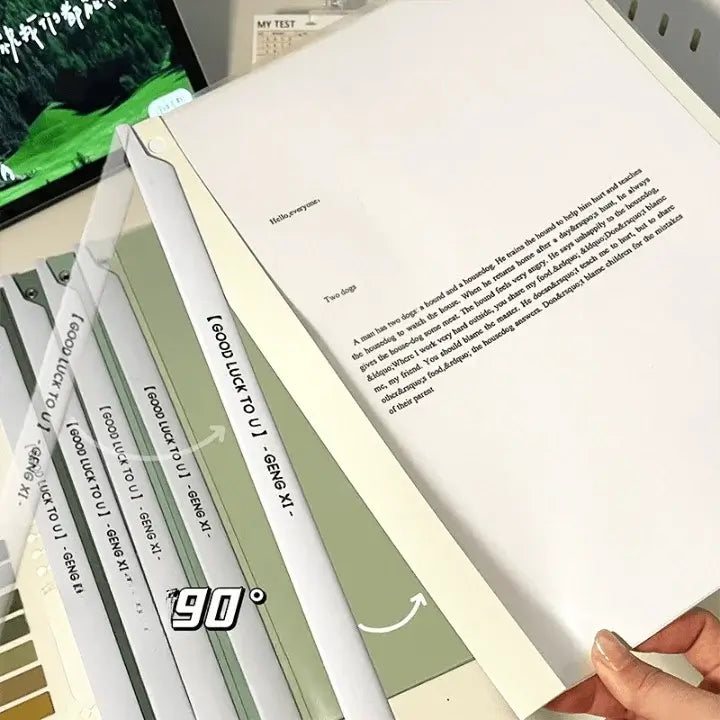 Open book with text held by a hand, with stationery items in the background