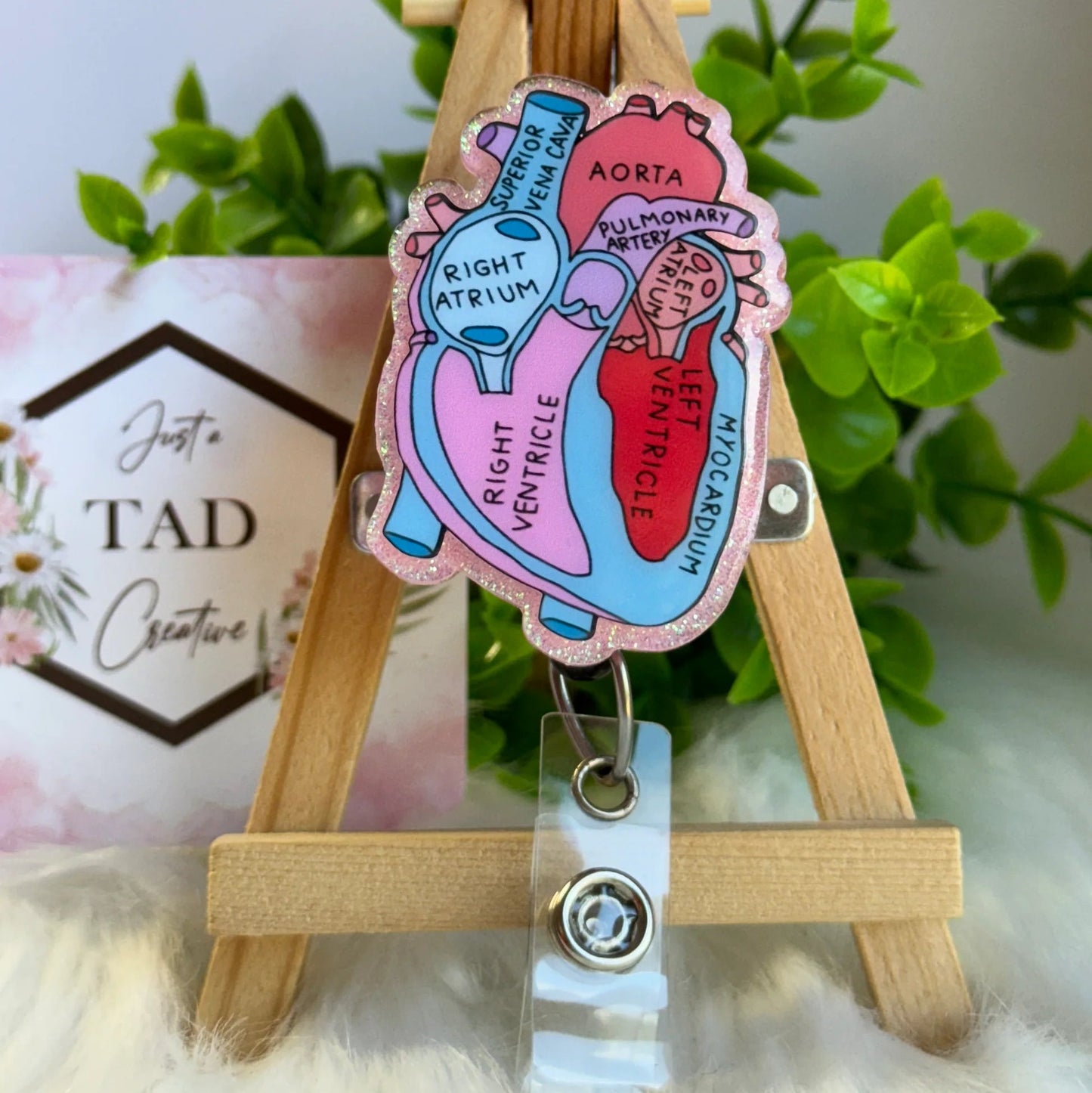 Colorful anatomical heart badge holder on a wooden stand with a blurred background