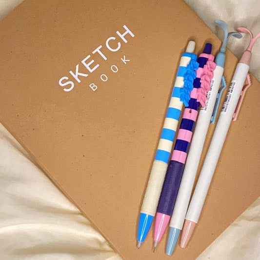 Sketchbook with colorful pens on a beige fabric background