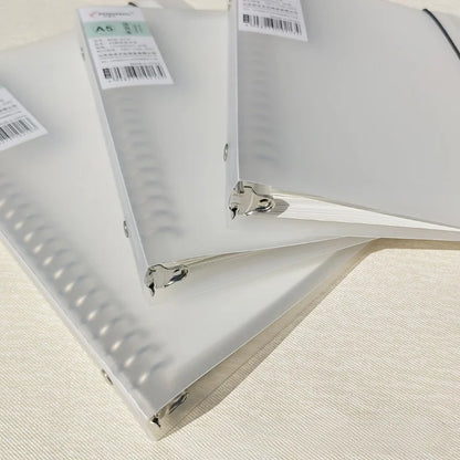 Clear plastic binders with metal rings on a textured surface