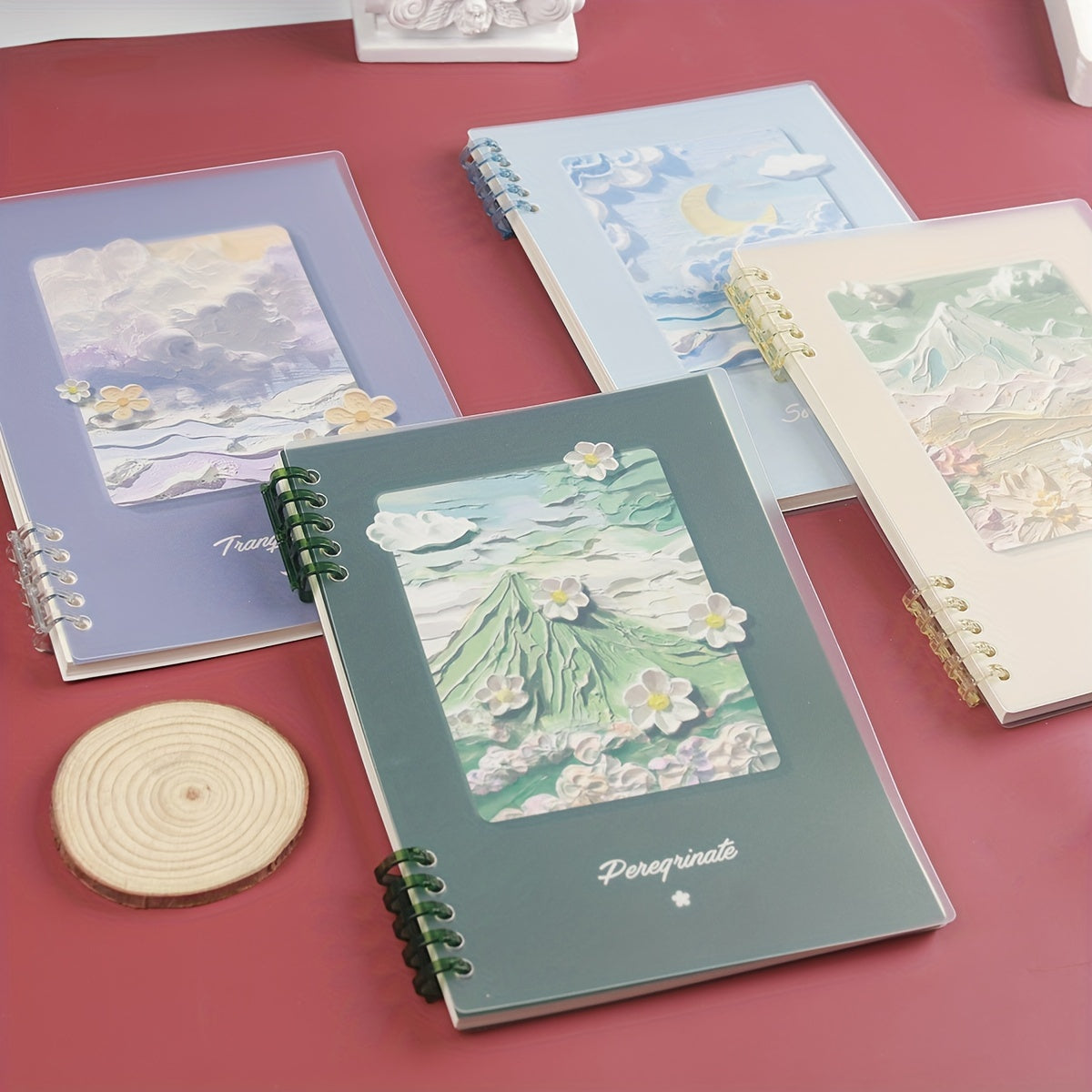 Three notebooks with artistic covers on a red surface