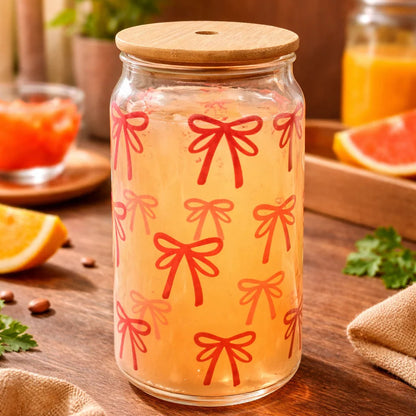 Jar of orange juice with red bow pattern on a wooden table with a plant in the background