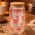 Clear glass jar with red bow pattern on a wooden surface with coffee beans and a cup.