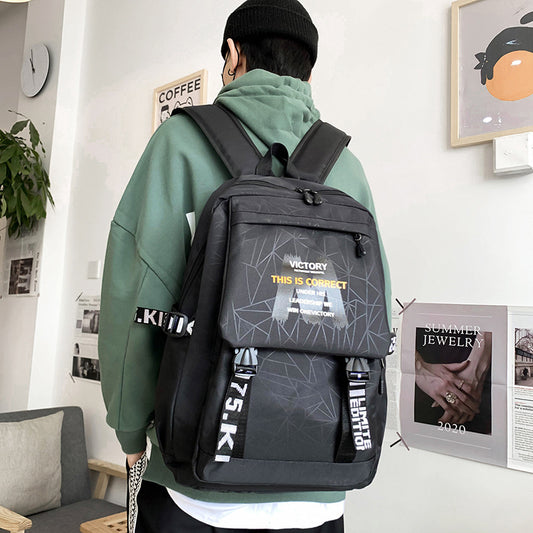 Person wearing a black backpack with geometric design and text in a room.