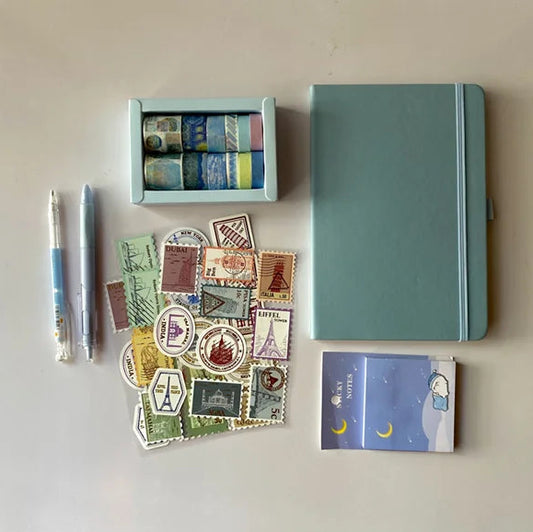 Collection of stationery items including a notebook, stamps, and pens on a light surface.