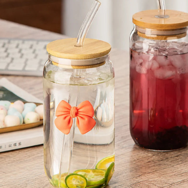 Two glass jars with wooden lids and straws on a table.