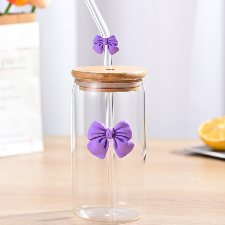 Glass tumbler with wooden lid and purple bow decorations on a light surface.