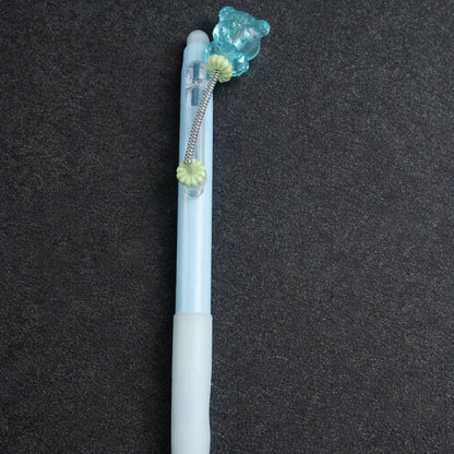 Pen with a decorative bear charm on a dark background