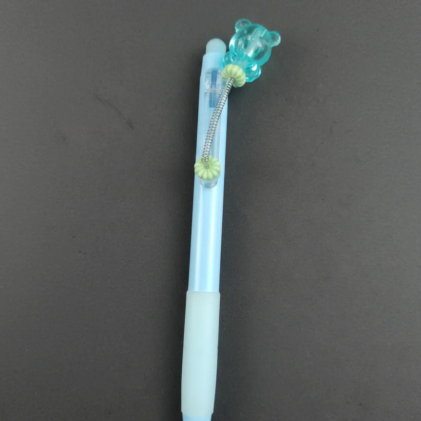 Blue pen with a bear-shaped clip on a dark gray background