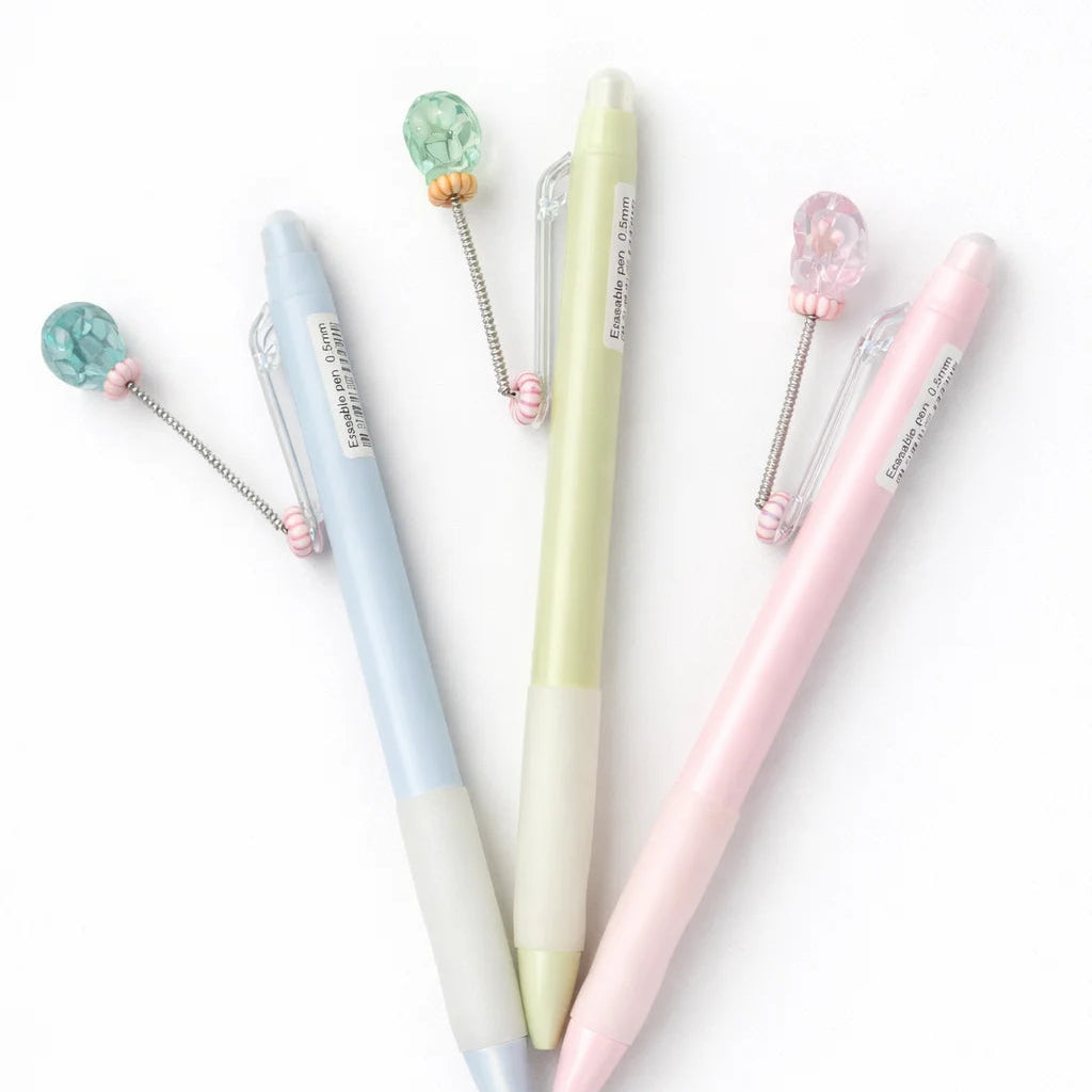 Set of three pastel-colored pens with decorative elements on a white background