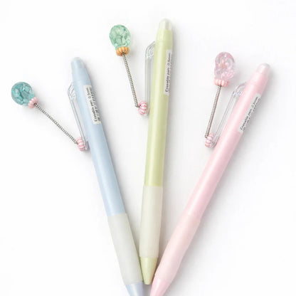 Set of three pastel-colored pens with decorative elements on a white background