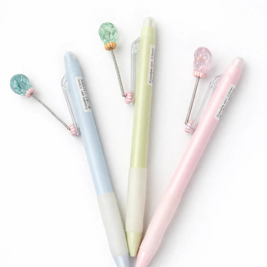 Set of three pastel-colored pens with decorative elements on a white background