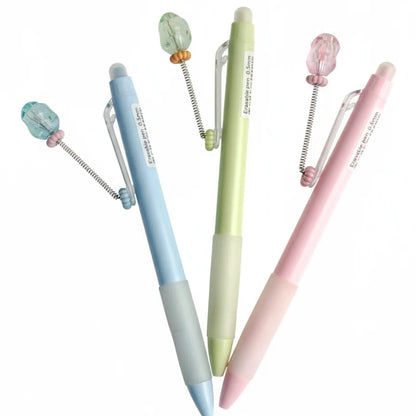 Three pastel-colored pens with decorative elements on a white background