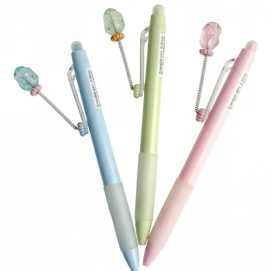 Three pastel-colored pens with decorative elements on a white background