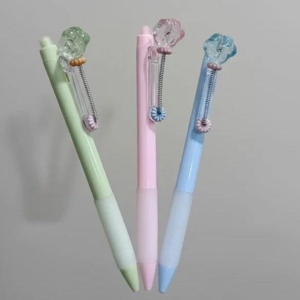 Three pastel-colored pens with decorative elements on a gray background