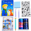 A curated stationery and art gift set arranged on a white background, including a 'Painte Prince' hardcover notebook with a boy and fox illustration, a second illustrated notebook, a blue sticky note pad, clear stamp sheets, tweezers, a blue pen, and multiple rolls of decorative washi tape in blue, pink, purple, and galaxy designs.