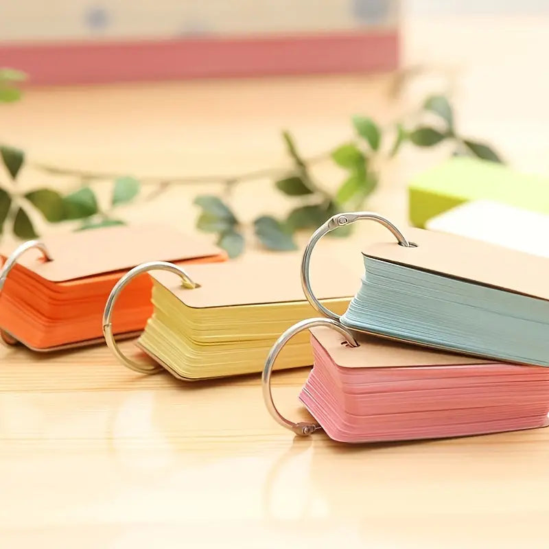 A set of colorful flashcards with metal binder rings, stacked and fanned out on a wooden surface.