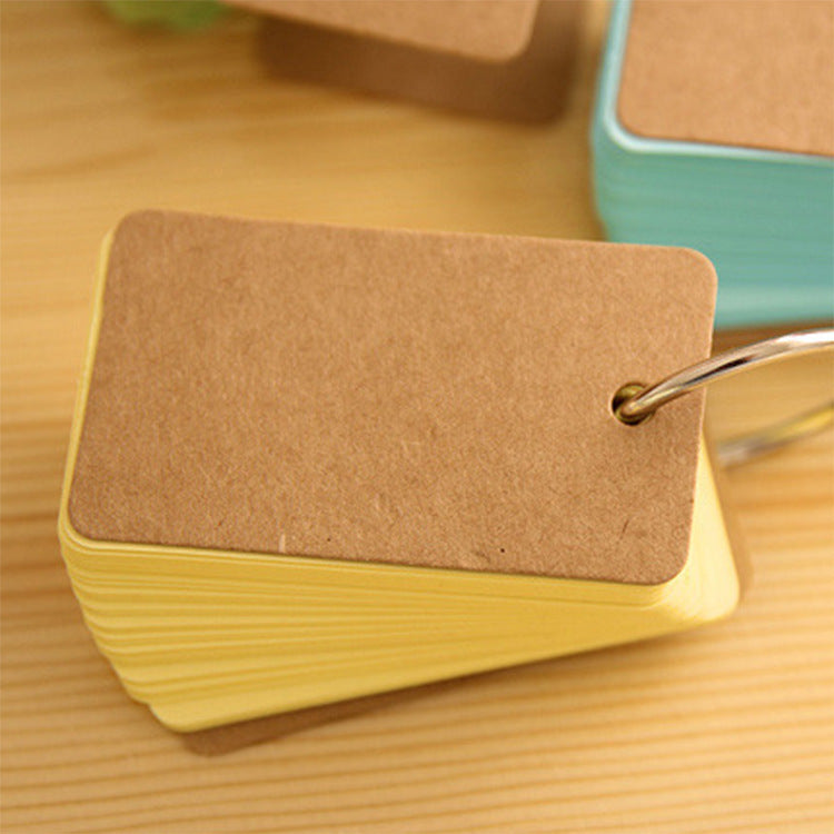 Stack of yellow cards with a brown card on top, held together by a metal clip, on a wooden surface.