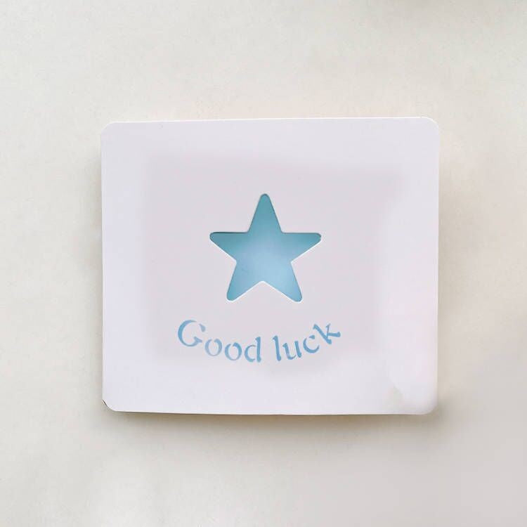 White card with a blue star and 'Good luck' text on a light beige background
