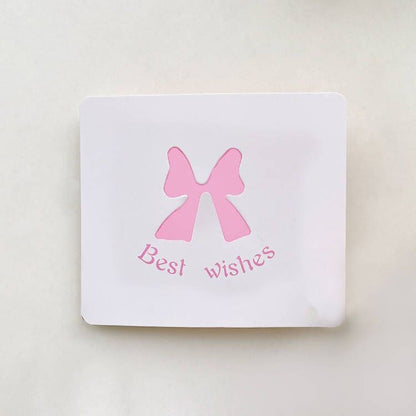 White card with a pink bow and 'Best wishes' text on a light beige background