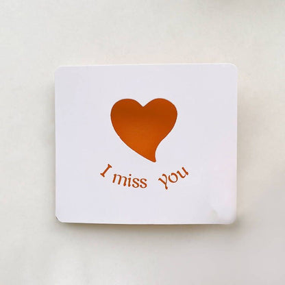 Card with an orange heart and 'I miss you' text on a white background